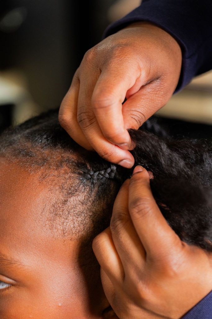 Stylist creating neat protective braids while caring for the client's edges